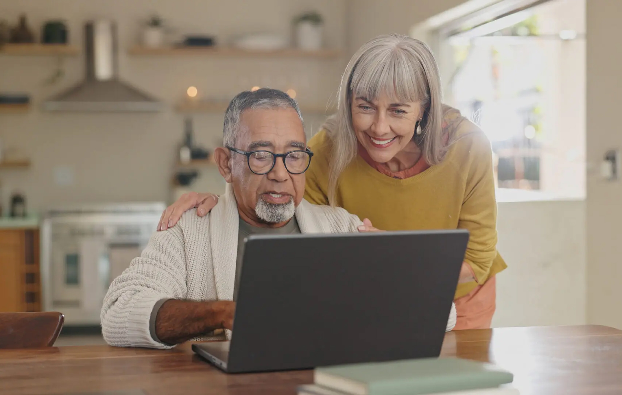Elderly couple use a laptop while sitting at home.